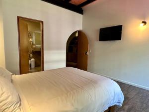 a bedroom with a white bed and a flat screen tv at Casa Raffaello in Mexico City