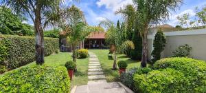 un jardín con árboles y una pasarela frente a una casa en Alquiler temporario Tandil LAS PALMERAS I, en Tandil