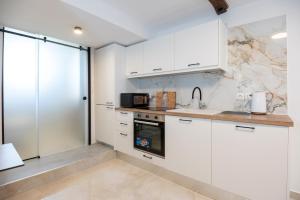 a kitchen with white cabinets and a sink at Solomon Royal Garden in Kritsá