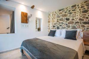 a bedroom with a large bed with a stone wall at Solomon Royal Garden in Kritsá +18 photos