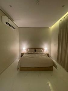 a bedroom with a bed and two lamps on two tables at AMA APARTMENT in Ar Rass