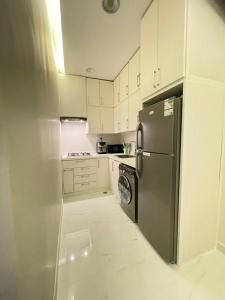 eine Küche mit einem Kühlschrank aus Edelstahl und weißen Schränken in der Unterkunft AMA APARTMENT in Ar Rass