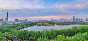 Marriott Executive Apartment Tianjin Lakeview في تيانجين: اطلالة على نهر مع مدينة في الخلف