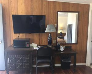 a bedroom with a desk with a television and a mirror at Robbie's Motel in Cache Creek