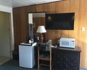 a room with a desk with a microwave and a refrigerator at Robbie's Motel in Cache Creek