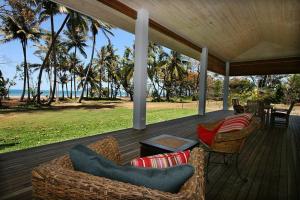 a porch with couches and chairs on the beach at Tropika - Absolute Beachfront in Mission Beach
