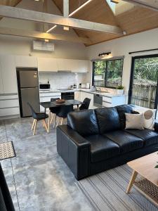 a living room with a black couch and a kitchen at Modern Two bedroom Oasis in Whangamata