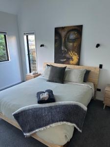 1 dormitorio con 1 cama grande y una pintura en la pared en Modern Two bedroom Oasis en Whangamata