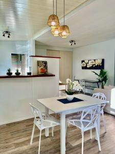 a kitchen and dining room with a white table and chairs at Tiaki Guesthouse - Cozy Modern Studio - 5min drive from the beach and Punaauia center in Punaauia