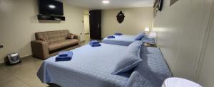 a bedroom with two beds with blue pillows and a couch at EDIFICIO RENZO Apart in Tarija