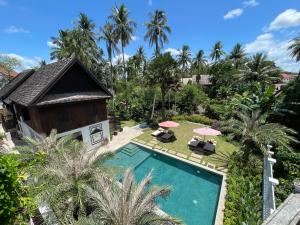 - une vue aérienne sur une villa dotée d'une piscine et de palmiers dans l'établissement Parasol Blanc, à Luang Prabang