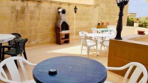 um pátio com uma mesa, cadeiras e um fogão em Masri Accommodation em Il-Pergla