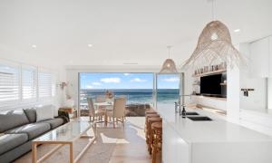 a living room with a couch and a kitchen with the ocean at Collaroy Beachfront Escape - New Listing in Collaroy