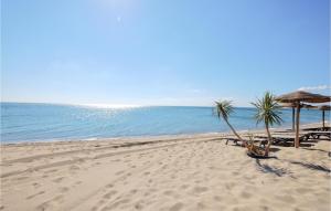 una playa con sillas y sombrillas y el océano en Nice Home In Torreilles With Kitchen, en Torreilles