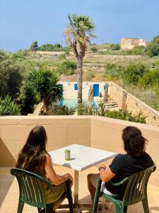 duas pessoas sentadas numa mesa a olhar para uma piscina em Masri Accommodation em Il-Pergla
