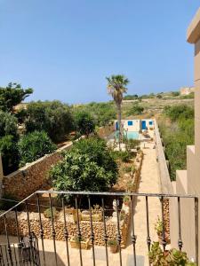 uma vista para um jardim a partir da varanda de uma casa em Masri Accommodation em Il-Pergla