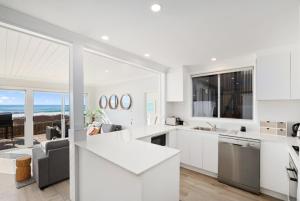a white kitchen with a view of the ocean at Collaroy Beachfront Hideaway - Parking and views in Collaroy