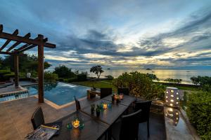 a patio with a table and chairs next to a pool at BeachFront Modern 4 Bedroom Pool Villa RV in Hua Hin