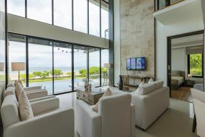 una sala de estar con muebles blancos y ventanas grandes. en BeachFront Modern 4 Bedroom Pool Villa RV en Hua Hin