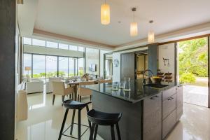 cocina abierta y comedor con encimera y taburetes en BeachFront Modern 4 Bedroom Pool Villa RV, en Hua Hin