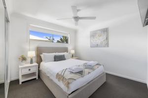 a white bedroom with a bed and a window at Ripples at ParkBeach in Coffs Harbour