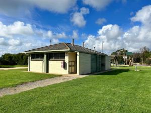 a small green and white house on a grass field at Wilsons Prom Holiday Park in Yanakie