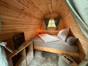 Cama pequeña en habitación de madera con TV en Ferienhaus im Wald en Borkwalde