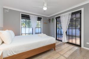 Un dormitorio con una cama y dos grandes ventanales. en 8 Elizabeth Parade, en Forster