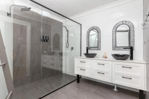 Un baño con dos lavabos y una ducha de cristal. en 8 Elizabeth Parade, en Forster 15 fotos más
