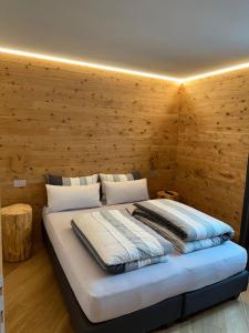 uma cama num quarto com uma parede de madeira em Chrys appartamenti em Valfurva