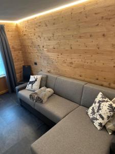 um sofá num quarto com uma parede de madeira em Chrys appartamenti em Valfurva