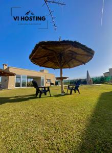 two benches sitting under an umbrella in a field at Vi Hosting Cabañas Premium in Salta