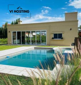 a house with a swimming pool in front of a building at Vi Hosting Cabañas Premium in Salta