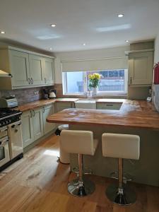 a kitchen with a large wooden counter with two bar stools at Honeycott in Crickhowell