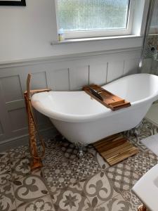 a white bath tub in a bathroom with a window at Honeycott in Crickhowell