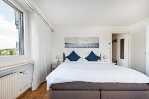 ein weißes Schlafzimmer mit einem großen Bett mit blauen Kissen in der Unterkunft Cooldis 6 !Gratis Parken, Free Parking! in Kreuzlingen