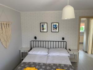 a bedroom with a bed with two tables and a white brick wall at AMBER Dębki in Dębki