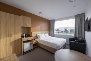 a hotel room with a bed and a desk and a table at Manha Hotel Auckland Airport in Auckland