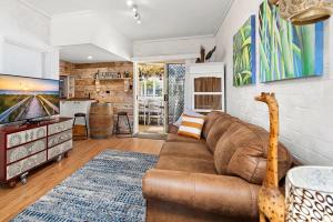 a living room with a brown couch and a kitchen at Fingal Pines Getaway, Apartment in Fingal Bay