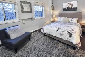 a bedroom with a bed and a chair and windows at Fingal Pines Getaway, Apartment in Fingal Bay