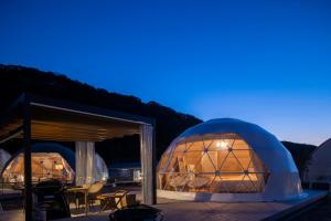 a couple of domes at night with a table and chairs at Glamping&Port結 in Shimada