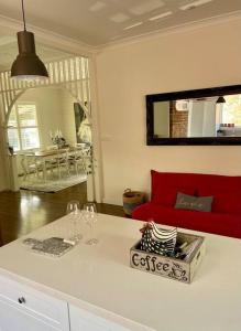 une cuisine avec un comptoir blanc, des verres à vin et un canapé rouge dans l'établissement Old Bakery Cottage Millthorpe, à Millthorpe