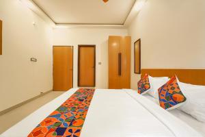 バンガロールにあるFabExpress Grand Viewのベッドルーム(カラフルなシーツを使用した大きな白いベッド付)