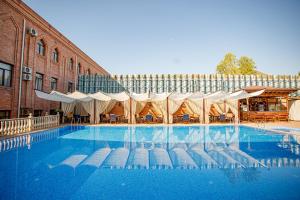 ein großer Pool mit Stühlen und Sonnenschirmen in der Unterkunft Ichan Qal'a Premium Class Hotel in Taschkent
