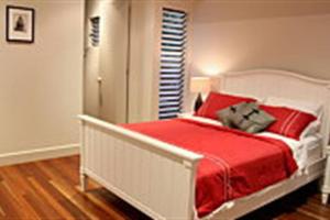 1 dormitorio con 1 cama con sábanas rojas y manta roja en Zama - Wongaling Beach - Beachfront Townhouse, en South Mission Beach
