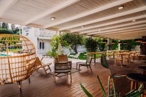 een patio met tafels en stoelen op een houten terras bij ELEŌNAS bohotel in Kavos
