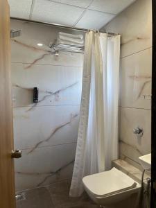 łazienka z białą zasłoną prysznicową i toaletą w obiekcie Click Hotel Tulsi Jamnagar w mieście Jamnagar