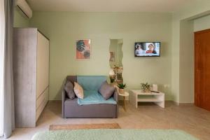 a living room with a couch and a tv on the wall at Heart Of The Town Studios Axd 2 in Alexandroupoli