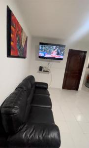 un sofá de cuero negro en una habitación con TV de pantalla plana en Cómodo y muy relajante alojamiento a 5 minutos de la playa, en Acapulco
