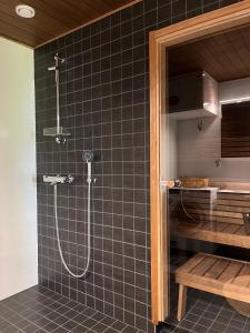 prysznic w łazience wyłożonej czarnymi kafelkami w obiekcie Tyylikäs saunallinen huoneisto Sotkamon satamassa w mieście Sotkamo